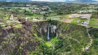 Yukarıdan, Sipisopiso kaya yüzeyinden aşağıya canlı yeşil bir vadiye doğru iniyor. Geçitleri ve köyleri güvenli bir şekilde kenarına tünemiş..