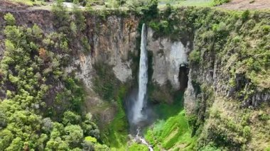 Yukarıdan, Sipisopiso kaya yüzeyinden aşağıya canlı yeşil bir vadiye doğru iniyor. Geçitleri ve köyleri güvenli bir şekilde kenarına tünemiş..
