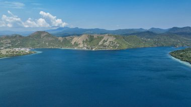 Küçük yerleşim yeri, yeşil tepelerin mavi sularla buluştuğu körfezi kucaklıyor. Uzak engebeli volkanik tepelerin ortasında kayıklarla benekli..