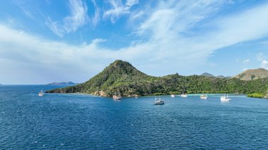 Zümrüt sularının dağılmış volkanik siluetler arasında engebeli uçurumlara çarptığı orman kaplı yarımadanın yanında yatlar kümelenir..