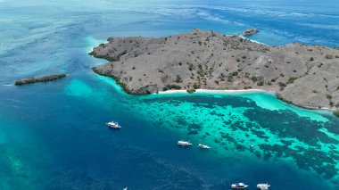 Canlı mercan desenleri Komodo 'nun altındaki turkuaz sığlıkları boyarken, dağılmış adalar ve uzak uyanışlar etraftaki gizli dalış noktalarını işaret ediyor..