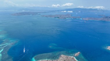Engebeli Komodo sırtları turkuaz koylara ve uzak adaların sonsuz bir mavi denizi noktaladığı beyaz kumlara doğru süpürüyor..