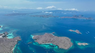 Padar Adası dramatik siluet çapaları. Dağınık adaların el değmemiş denizinde engebeli komşularla çevrili turkuaz ambarlar..