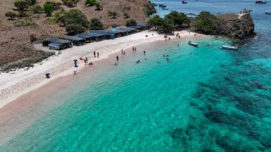 Yukarıdan bakıldığında, Pembe Kumsal, gölgelik ağaçlar ve şnorkellerle kaplı pastel kıyı şeridini gözler önüne seriyor..