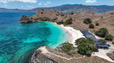Komodo Adası Pembe Sahili kayalık bir burnun altında, pembe kum ve turkuaz gölünün çerçeveli kır kulübeleri ve dağınık ağaçlarla çevrili..