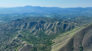 Yumuşak yontulmuş tepeler ve orman vadileri Flores boyunca uzanır, gür, engebeli bir manzara sisli mavi tepelere dönüşür..