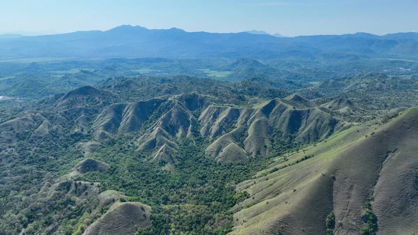 Yumuşak yontulmuş tepeler ve orman vadileri Flores boyunca uzanır, gür, engebeli bir manzara sisli mavi tepelere dönüşür..