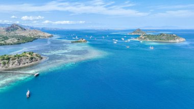 Komodo engebeli zirveleri, demirlemiş tekneler ve parlayan resiflerden oluşan bir denizden yükselir. Ada hayatının ve sonsuz okyanusun ebedi manzarası..