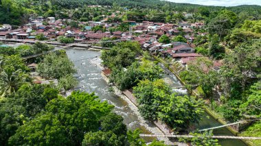 Bukit Lawang kıyılara tutunurken Bohorok Nehri orman tepelerini oyuyor. Canlı bir Sumatra köyü koyu yeşile bürünmüş..
