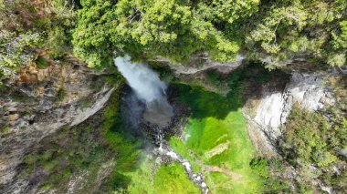 Köpüren beyaz bir sütun zümrüt yosunlara çarpıyor. Sispiso Piso şelalesi manzarasında. Sprey, kayayla orman arasındaki çizgiyi bulanıklaştırıyor..