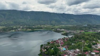 Yukardan, Tuk Tuk bir ejderha kuyruğu gibi Toba Gölü 'ne doğru kıvrılır, kümelenmiş çatıları ve salınımları sakin volkanik kıyı şeridine sarılır..