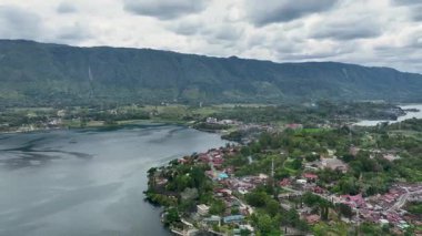 Toba Gölü yüzeyinden yükselen karanlık tepeler Tuk Tuk yarımadasındaki kara kara kara gökyüzünün altında dağılmış göl kenarındaki köyleri gölden cüce gibi gösteriyor..