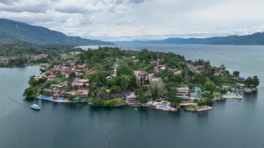 Canlı mavi feribot Samosir 'de Tuk Tuk' a doğru süzülüyor yemyeşil tatil köyleri ve Tobas Gölü 'nün derin suları arasında Sumatra cenneti.