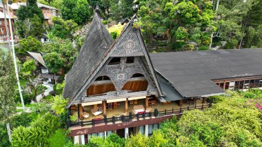Palmiye ve çamlardan oluşan bir ormanda gizlenen bu süslü Batak çatısı yamaçtaki bir köyü taçlandırıyor ve Toba Gölü 'ndeki Samosir' in ebedi ruhunu yakalıyor..