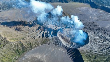 Bromo konisi engin Tengger Caldera kâsesine hayalet tüyleri salıyor. Duman ve taş senfonisi içindeki engebeli zirvelerle süsleniyor..