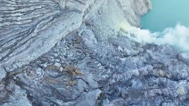 Kawah İjen krater zeminindeki kayaların havadan kapatılması. Mineral yataklarının altın damarları canlı maviye karşı parlıyor ve Doğu Java 'daki diğer dünya dışı jeotermal sanatlar volkanını sergiliyor..