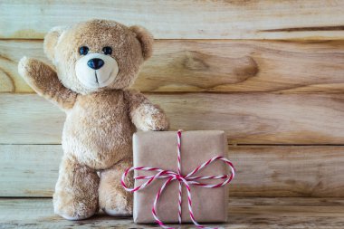 Oyuncak ayı ayakta yanında kahverengi hediye kutusu