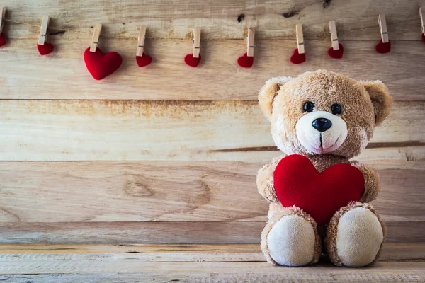 Osito de peluche sosteniendo una almohada en forma de corazón — Foto de Stock