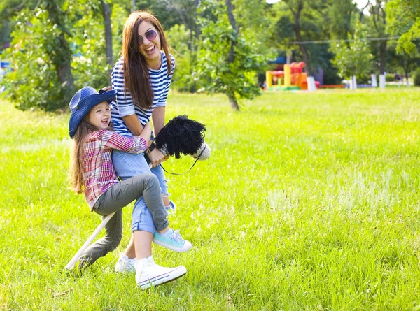 Divertida mamá e hija y caballo de juguete —  Fotos de Stock