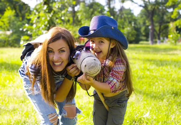 Lustige Mutter und Tochter und Spielzeugpferd lizenzfreie Stockfotos
