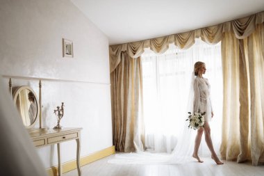 İç kısımda güzel sarışın bir gelinin portresi. Bornozlu genç gelin. Gülümseyen ve tatlı kız duruyor. Yüksek kalite fotoğraf