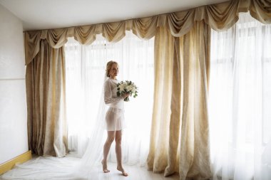 İç kısımda güzel sarışın bir gelinin portresi. Bornozlu genç gelin. Gülümseyen ve tatlı kız duruyor. Yüksek kalite fotoğraf