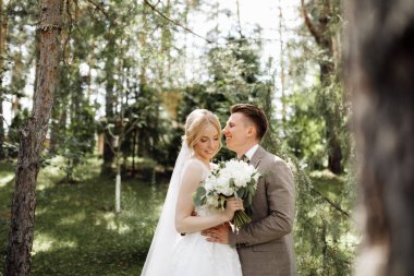 Baharın arka planında güneşli yeşil ormanda lüks bir gelin ve damat. Birbirine aşık bir çift. Yüksek kalite fotoğraf