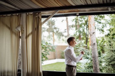 Mutlu yakışıklı damat sabah giyiniyor. Damat düğün hazırlıkları için bir takım elbise giyer. Yüksek kalite fotoğraf