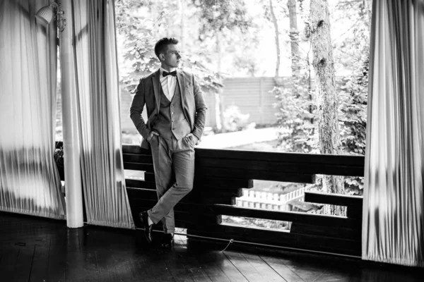 ビジネススーツのスタイリッシュな若い男 ハンサムな新郎ポージング 窓のそばでポーズをとるのに適した新郎 高品質の写真 — ストック写真