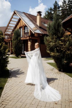 Yeşil bir bahçede duran, elinde çiçek ve yeşillik buketi olan bir gelinlik içinde gelin. Yüksek kalite fotoğraf