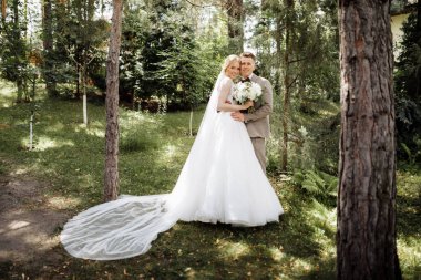 Baharın arka planında güneşli yeşil ormanda lüks bir gelin ve damat. Birbirine aşık bir çift. Yüksek kalite fotoğraf