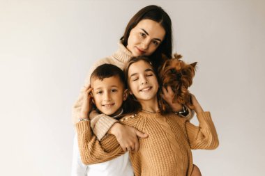 Anne beyaz arka planda kızına ve oğluna sarılıyor. Yüksek kalite fotoğraf