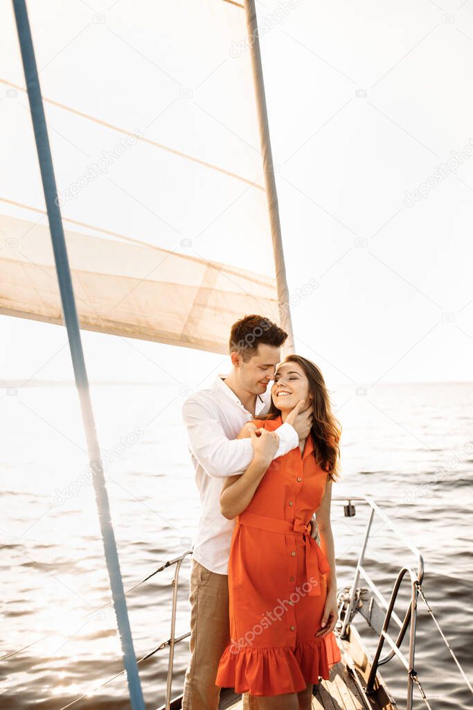 A couple in love on the edge of the yacht hug and hold hands, show love, strong hugs, blue sea, white sailing yacht. Happy valentines day . High quality photo