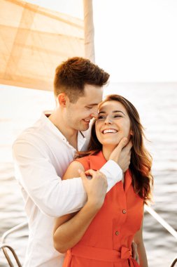 Yatın kenarında birbirine aşık bir çift el ele tutuşur, sevgi gösterir, güçlü kucaklaşmalar, mavi deniz, beyaz yelkenli yat. Sevgililer günün kutlu olsun. Yüksek kalite fotoğraf