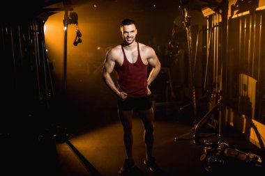 Kaslı adam gülümser ve spor salonunda vücudunun kaslarını gösterir. - Evet. Yüksek kalite fotoğraf