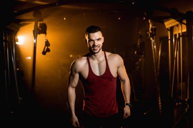 Kaslı adam gülümser ve spor salonunda vücudunun kaslarını gösterir. - Evet. Yüksek kalite fotoğraf