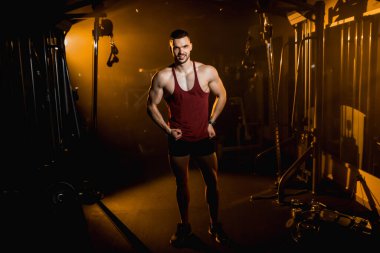 Kaslı adam gülümser ve spor salonunda vücudunun kaslarını gösterir. - Evet. Yüksek kalite fotoğraf
