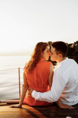 Bir yatta, denizin arka planında nazikçe ve dokunaklı kucaklaşmalar, gün batımında birbirine aşık bir çift. - Evet. Yüksek kalite fotoğraf