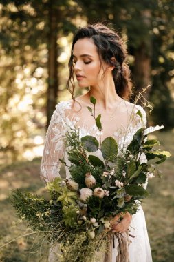 Orman arka planında buketi olan beyaz elbiseli güzel bir gelin. Yüksek kalite fotoğraf