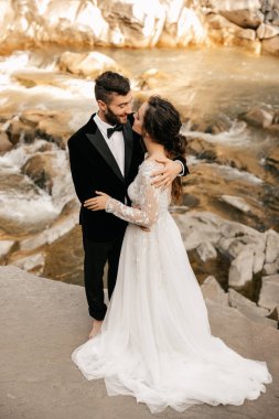 Şelale ve taştan bir nehrin arka planında güzel bir düğün çifti. Yüksek kalite fotoğraf