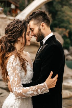 Güzel bir düğün çifti taşların arkasında gülüp öpüşüyor. Yüksek kalite fotoğraf