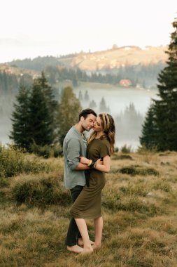 Birbirlerine aşık mutlu genç bir çift açık havada dağlarda sarılıp gülüyor. Yüksek kalite fotoğraf