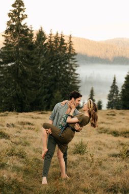 Sevgi dolu bir çift, dağların arka planında romantik poz veriyor, adam kızı eğiyor. Yüksek kalite fotoğraf