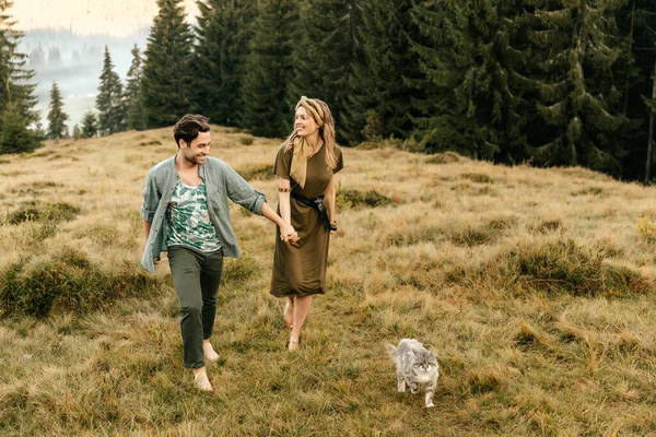 A beautiful couple in love are walking with the cat and smiling cheerfully in nature. High quality photo