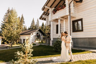 Gelin ve damat otelin bölgesinde sarılıyor, yeni evliler yürüyor. Yüksek kalite fotoğraf