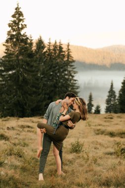 Sevgi dolu bir çift, dağların arka planında romantik poz veriyor, adam kızı eğiyor. Yüksek kalite fotoğraf