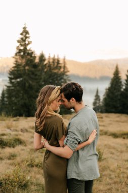 Genç ve mutlu bir çift. Birbirlerine sarılıyorlar, gülümsüyorlar ve dağlarda eğleniyorlar. Yüksek kalite fotoğraf