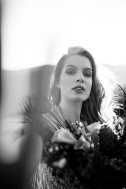 Beyaz gelinlik giymiş güzel bir gelinin portresi bir buketle dağlarda duruyor ve gülümsüyor. Yüksek kalite fotoğraf