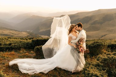 Güzel, mutlu, mutlu, birbirine aşık genç bir çift, dağlarda sarılıyor, arka planda güzel bir düğün çifti. Yüksek kalite fotoğraf