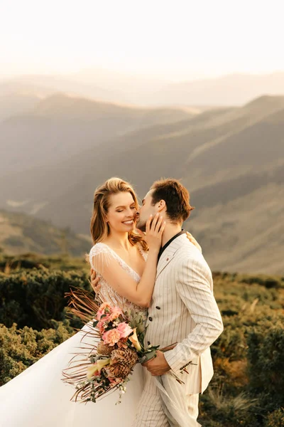 Güzel, mutlu, mutlu, birbirine aşık genç bir çift, dağlarda sarılıyor, arka planda güzel bir düğün çifti. Yüksek kalite fotoğraf